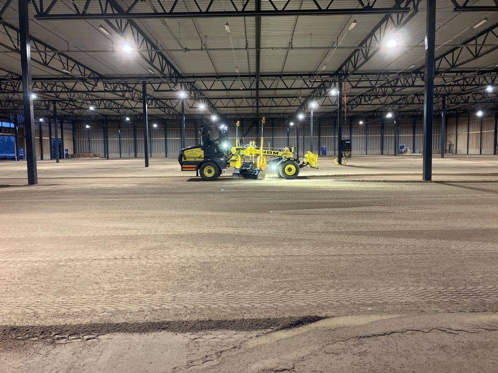 Väghyvel justerar av ytan inne i en ny logistikhall