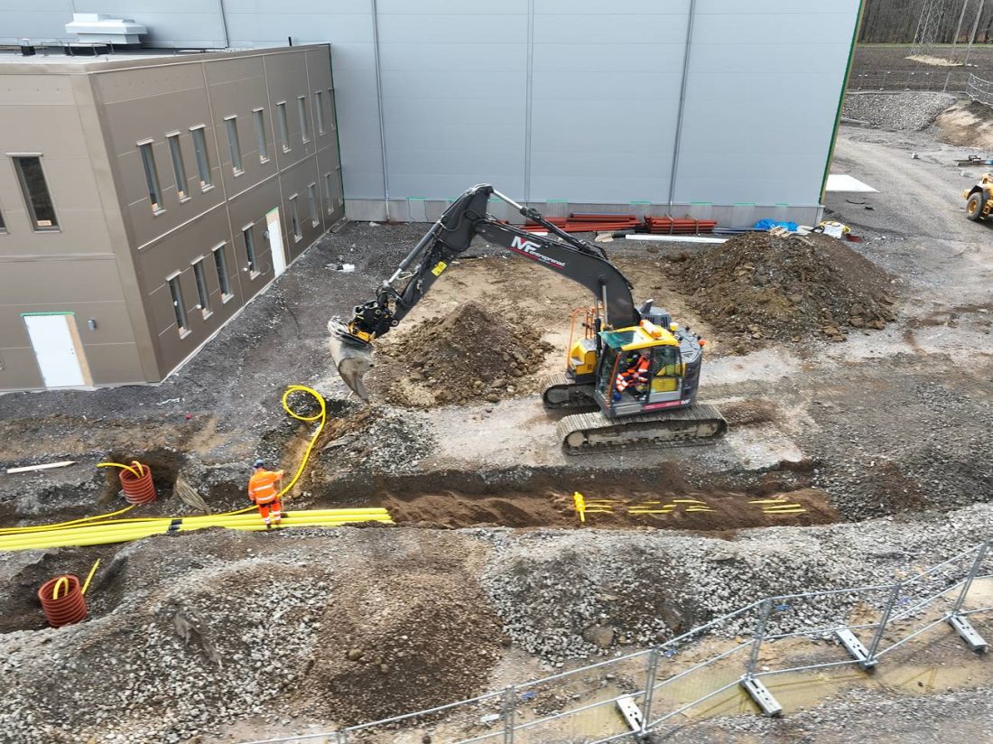 Grävmaskin lägger kabelrör i schakt